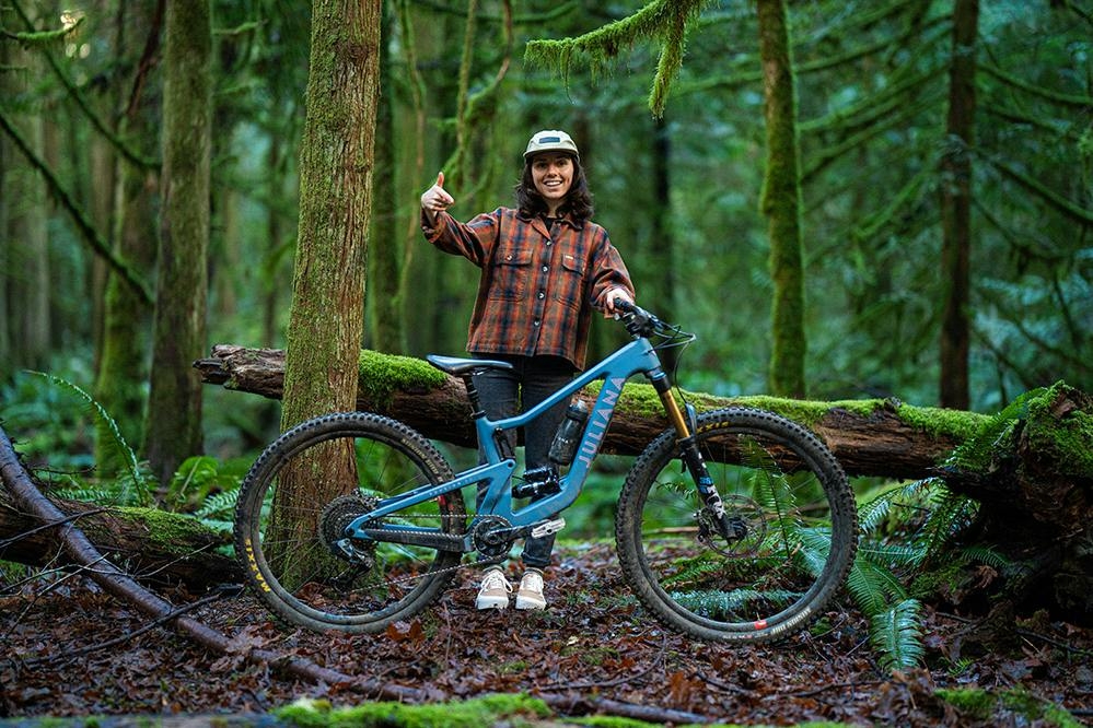 Delilah Cupp standing with her mountain bike in a green mossy forest