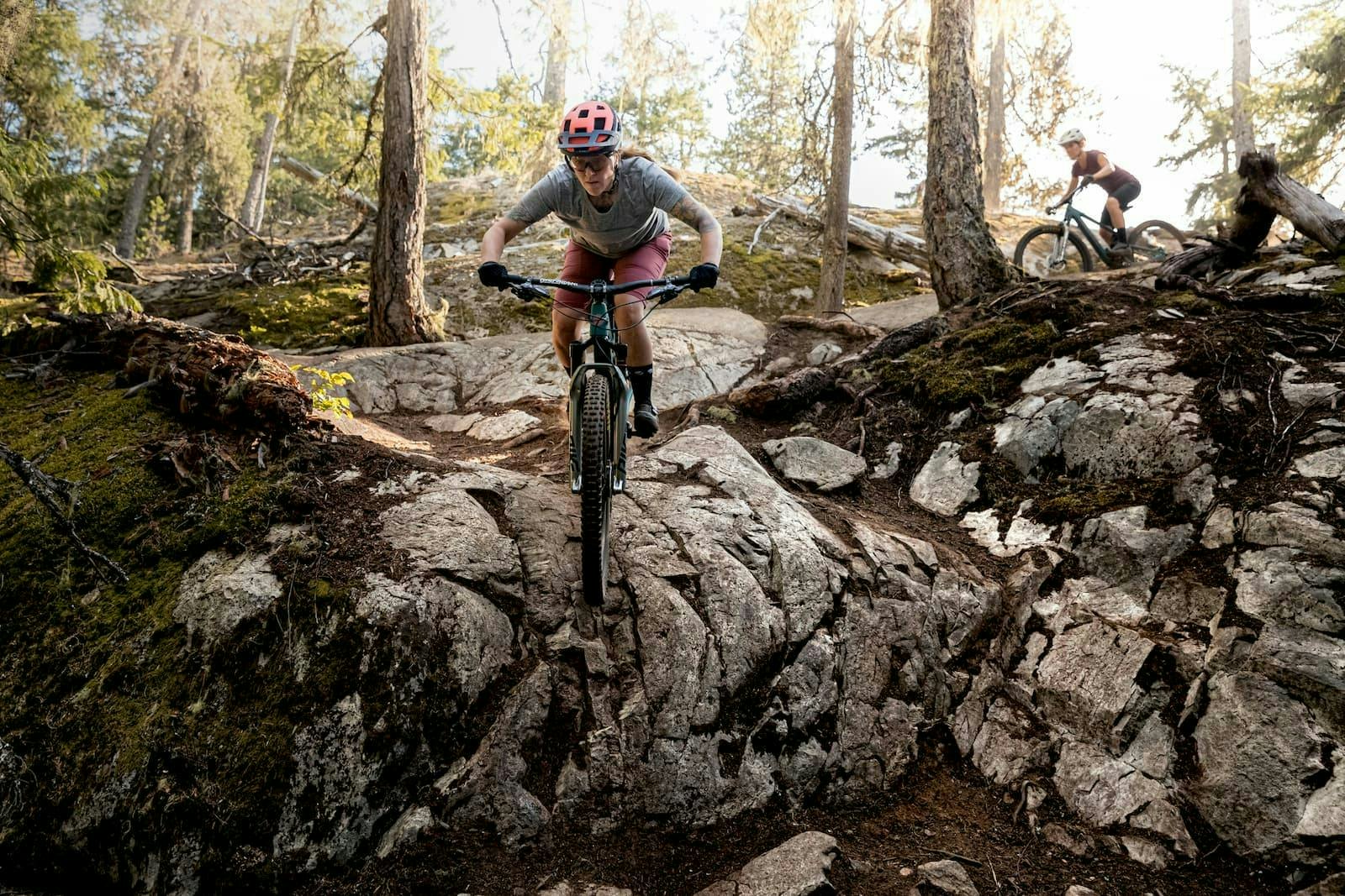 Mountain biker - Sarah Leishman descending through the forest on a rocky trail