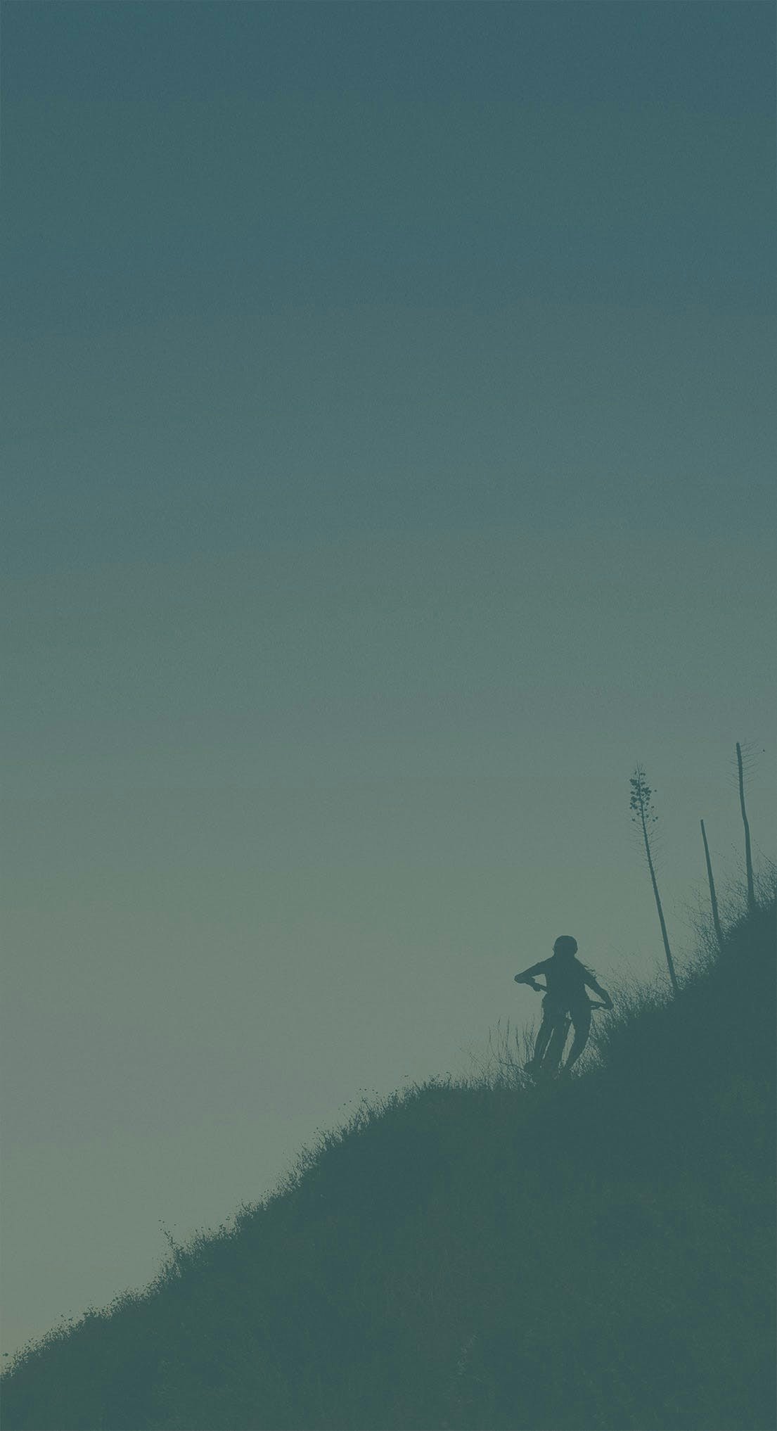 A silhouette of Juliana Rider Hailey Elise mountain biking on a hillside
