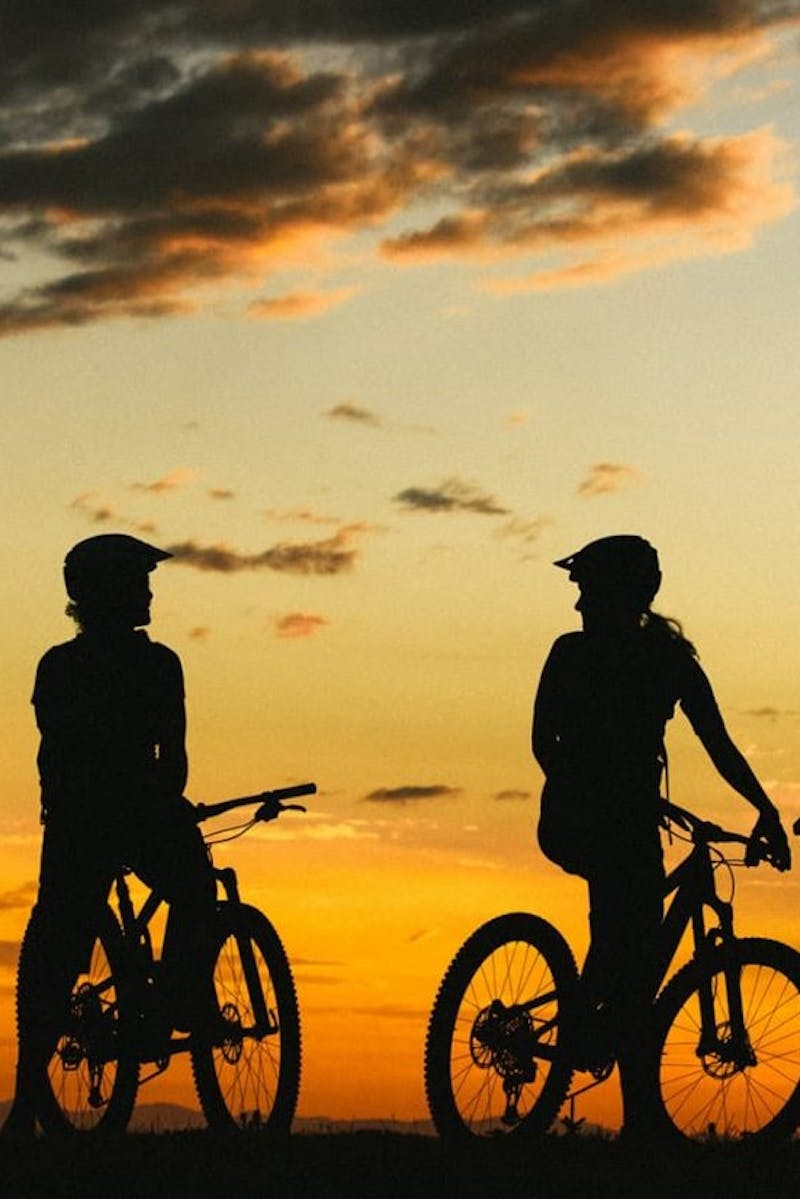 3 mountain bikers sitting on their bikes in the sunset