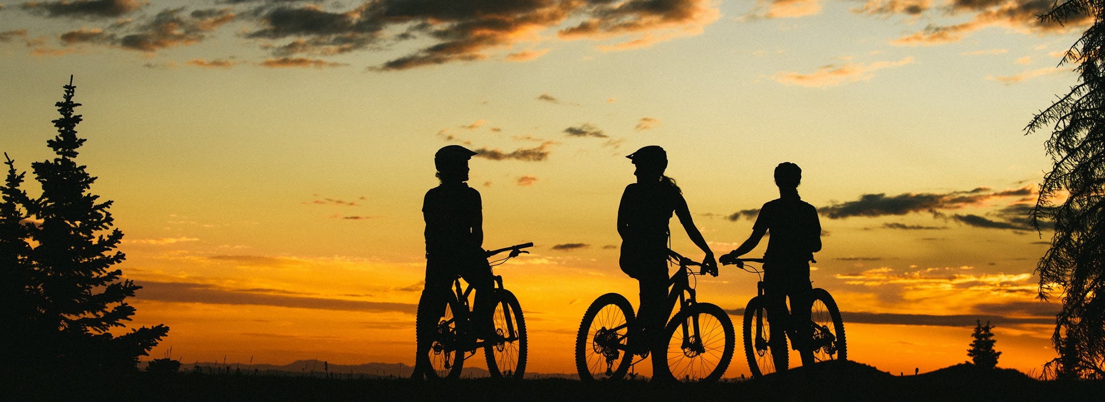 3 Juliana Bicycles riders sitting on their mountain bikes, watching the sunset