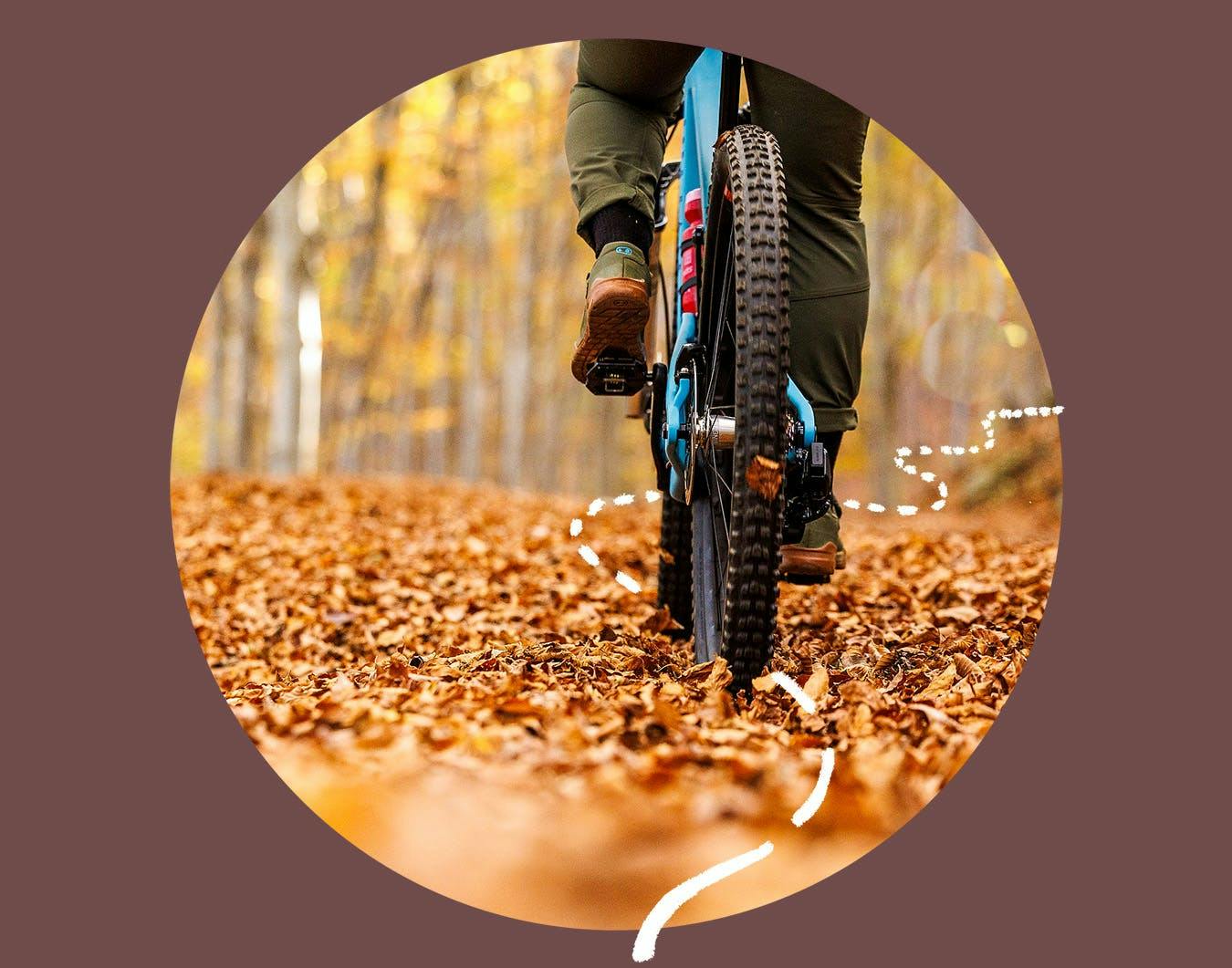 A mountain biker riding the Juliana Bicycles Joplin over a leaf covered trail