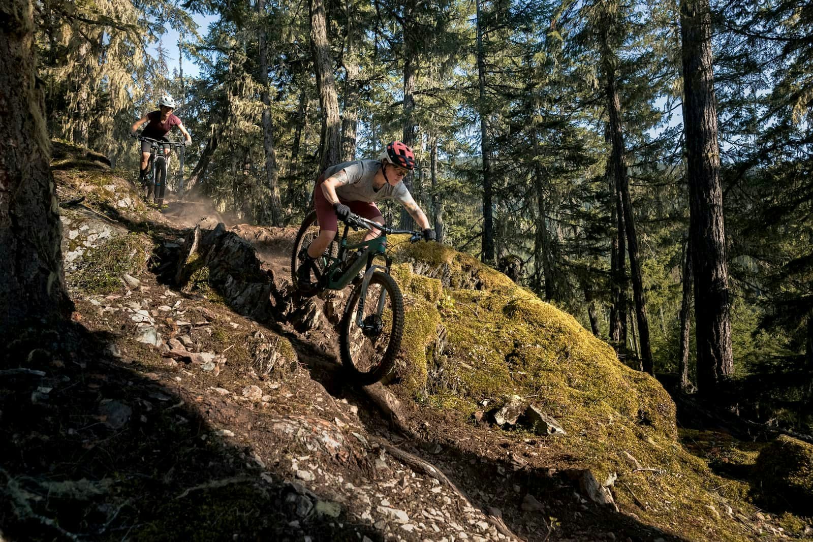 Mountain biker - Sarah Leishman descending through the forest on a dusty singletrack trail